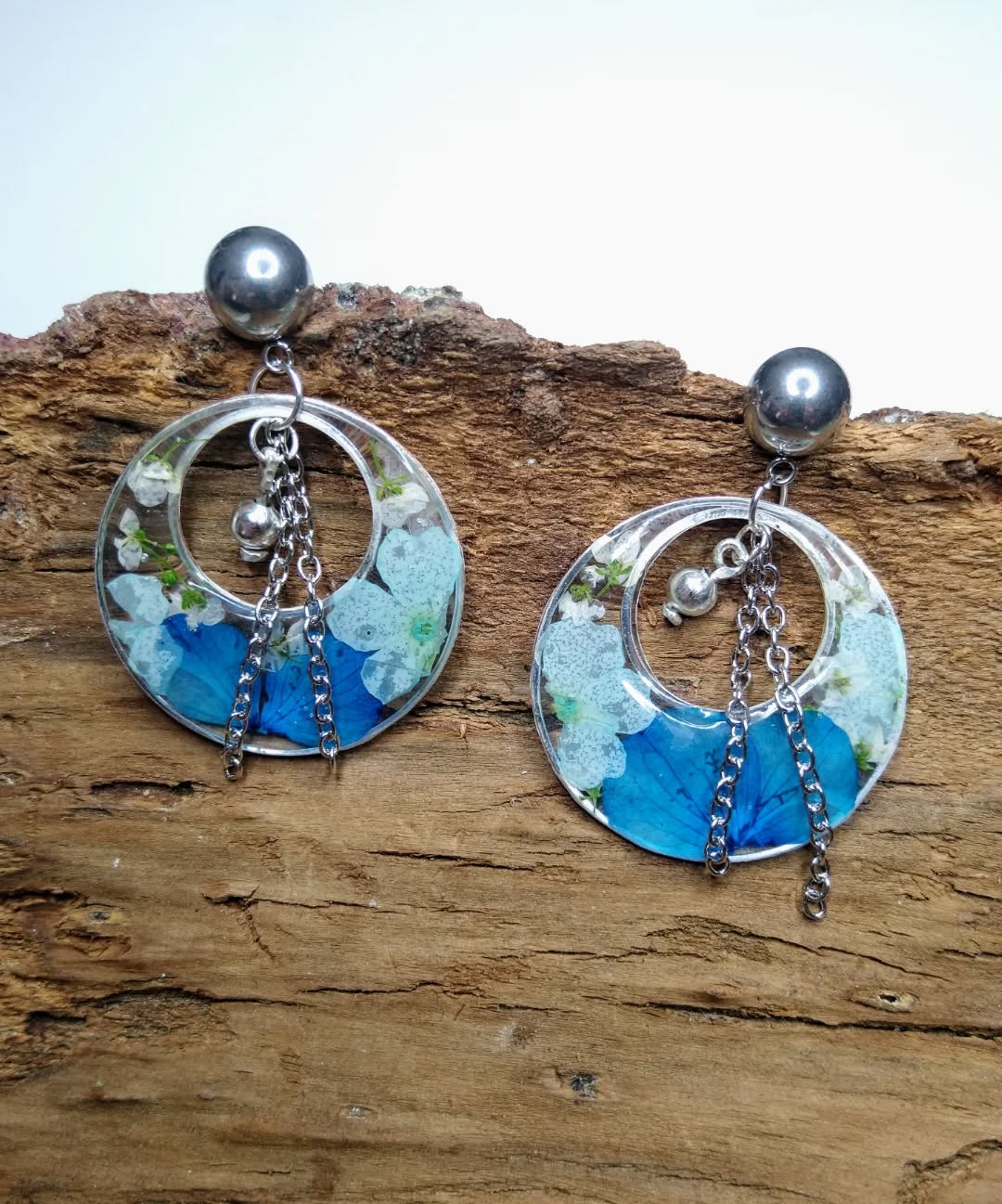 Boucles d'oreilles pendantes argentées avec inclusion de fleurs séchées bleues et blanches.

#bijouxartisanaux #jewelry #fleursséchées #bijouxcréateur #bouclesdoreilles #handmade